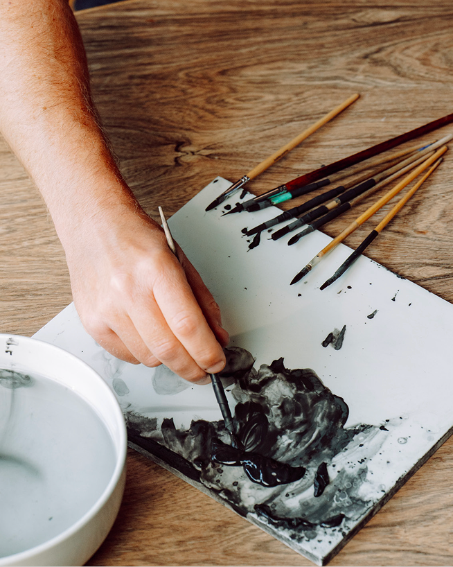 Royal Delft artisan practicing brushwork on a tile